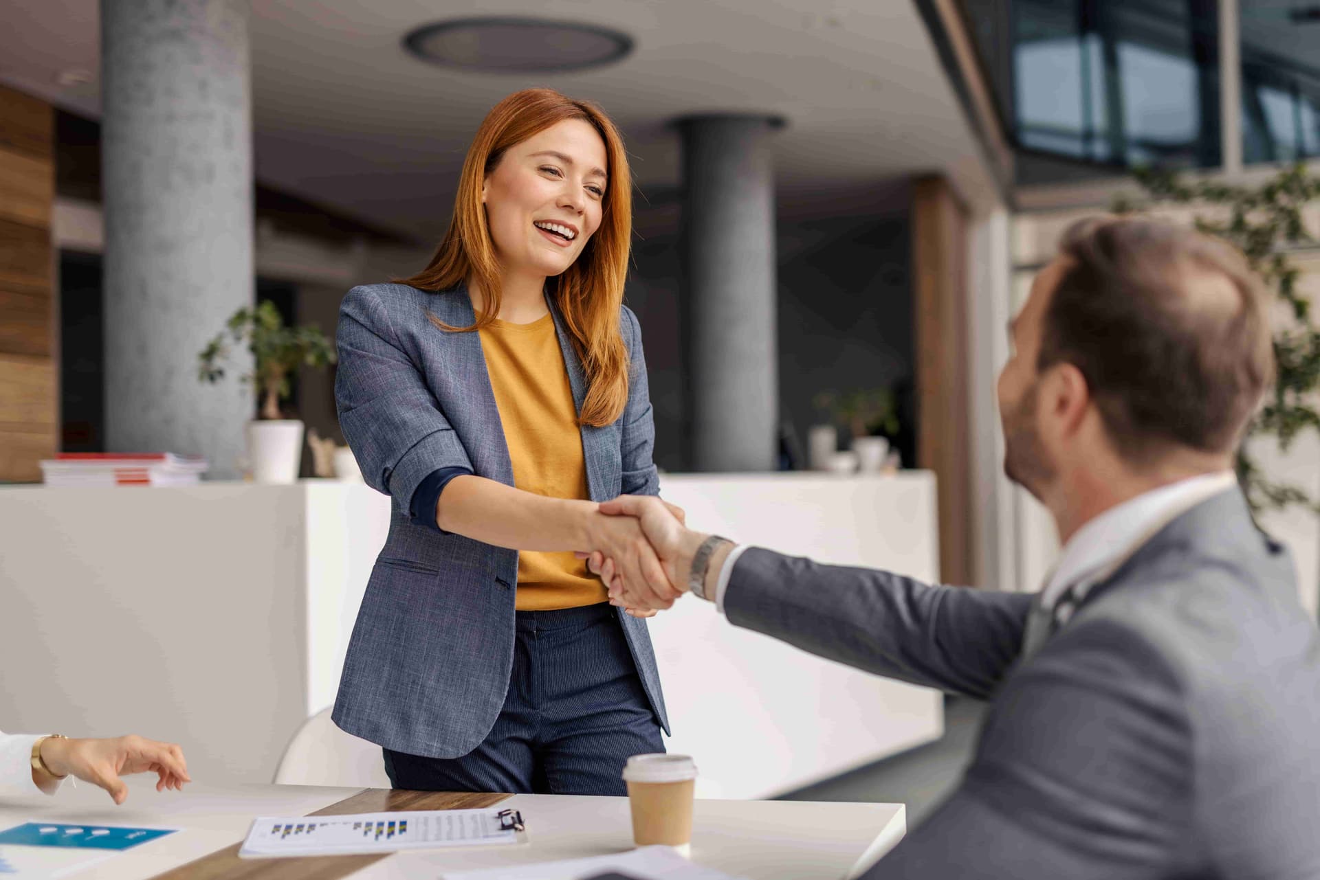 smiling female executive shaking hands with colleague